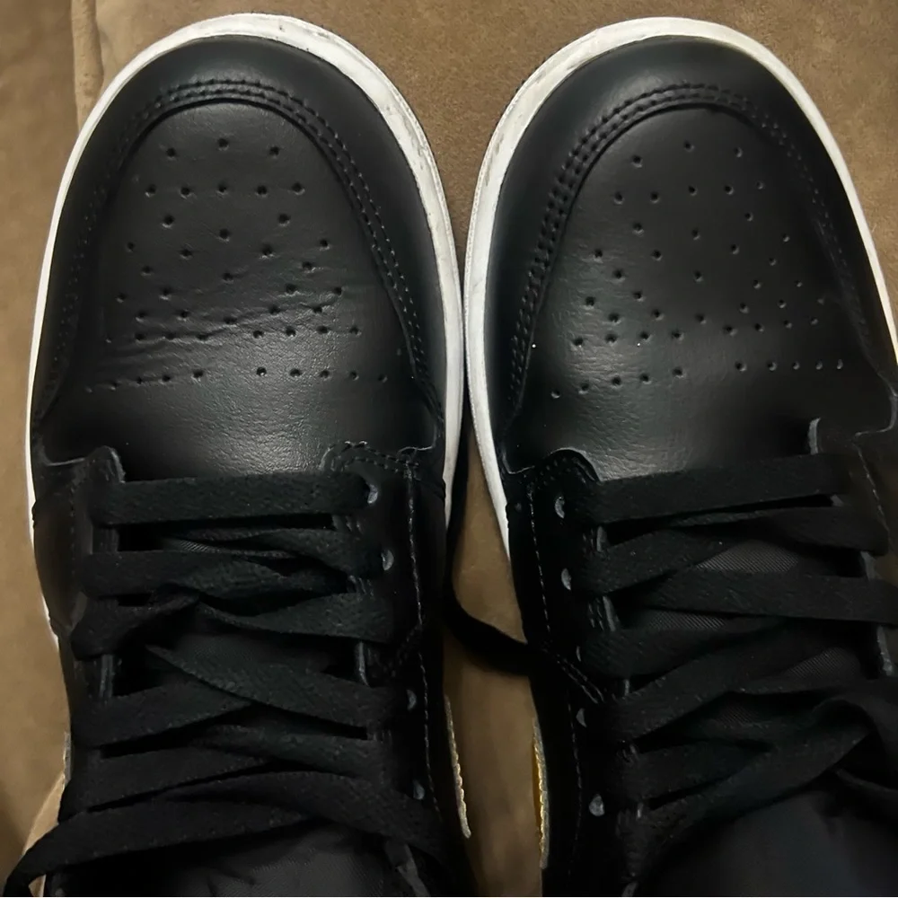 Nike Air Jordan 1 Mid in the black, metallic gold, and white colorway